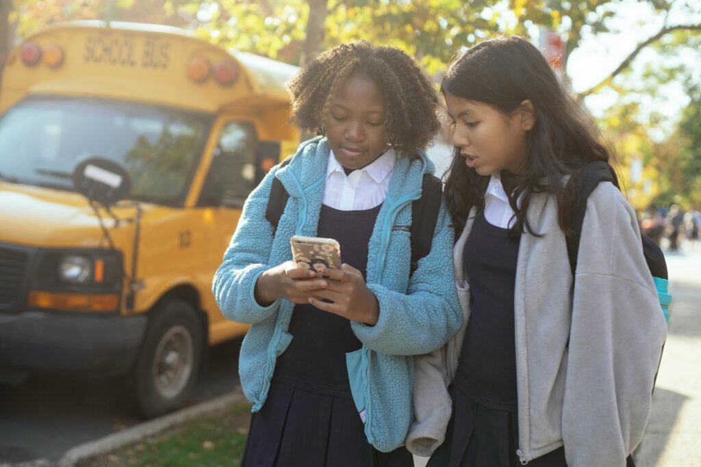 Two schoolgirls using a phone near a