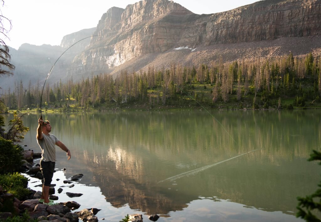 Man fly fishing in serene alpine lake,